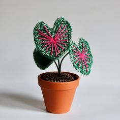 a crocheted potted plant with pink and green hearts on it's leaves