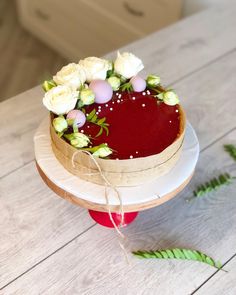 a cake with flowers on it sitting on top of a wooden table next to a plant