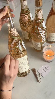 a person holding a wine bottle in front of several bottles on a table with candles