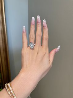 a woman's hand with pink and white nail polish holding a diamond ring