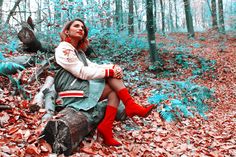 a woman sitting on top of a tree stump in the woods