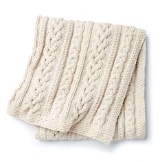 two white knitted blankets folded on top of each other, one with cabled details