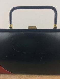 "Vintage 1960's frame purse has a rectangle shape; red and blue color blocked design; top handle; top clasp closure; interior pockets; interior lining; and purse feet on the bottom. The condition of this item = GOOD (Marks and scratches throughout; see last pics for details). BRAND: Unknown MEASUREMENTS Length = 6\" Width = 14\" Depth = 2.25\" Strap Length = 2.75\" THINGS TO KNOW: Measurements were taken with the garment laying flat. \"Fits like\" sizes are a rough estimate; please review the me Retro Rectangular Box Bag For Evenings, Red Rectangular Box Bag For Evening, Red Rectangular Box Bag For Formal Occasions, Retro Rectangular Evening Box Bag, Vintage Box Bag With Detachable Handle For Evening, Red Rectangular Evening Box Bag, Vintage Square Box Bag, Red Vintage Square Bag, Vintage Evening Box Bag With Detachable Handle