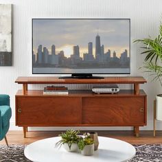 a flat screen tv sitting on top of a wooden entertainment center in a living room