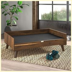 a wooden coffee table sitting on top of a rug next to a potted plant