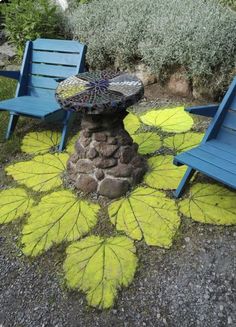 two blue chairs sitting next to each other on top of a patch of yellow leaves