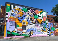 a large mural on the side of a building in front of a parking lot with parked cars