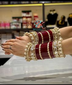 a woman's hands with bracelets and rings on display in a jewelry store