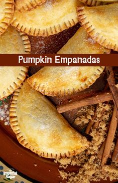 pumpkin empanadas on a plate with cinnamon sticks in the middle and an orange background