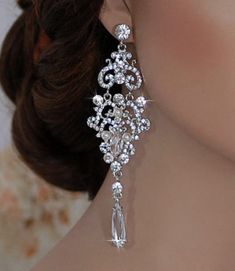 a close up of a woman's face wearing earrings with pearls and crystals on them