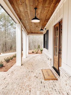 the front porch is lined with white pillars and brick walkways that lead up to two large windows