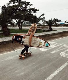 a woman is walking down the street with her surfboard