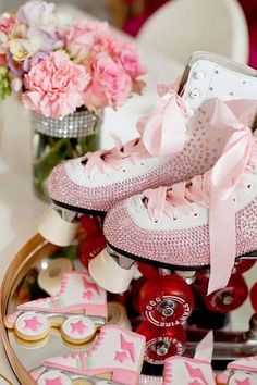 pink roller skates with bows and cookies on the table in front of them,