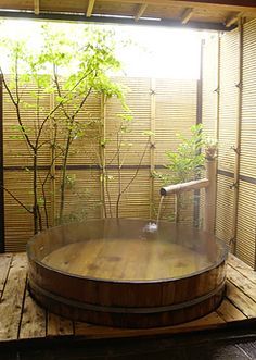 an outdoor hot tub in the middle of a wooden deck with bamboo screens behind it