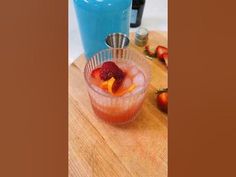 a drink in a glass with strawberries and oranges on the table next to it