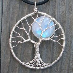 a tree of life pendant with a blue stone in the center on a black cord necklace