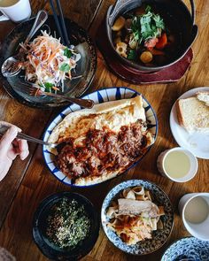 people sitting at a table with plates of food and bowls of soup on the table