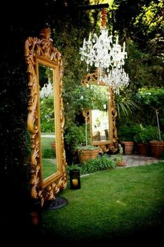 an ornate gold mirror sitting on top of a lush green field