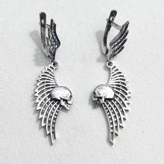 Skull and Wing Earrings Add a touch of edge to your style with these Skull and Wing Earrings. Crafted from solid sterling silver, these earrings feature an intricately detailed skull paired with an elegant wing design, weighing approximately 4.7 grams. They are perfect for those who appreciate unique, handcrafted jewelry with a gothic flair. ◆ Features: SKU: 41024 Brand new sterling silver 925 ring. Not plated!, 100% solid silver metal! Approx. weight of the product - 4.7g. Manufacturing and cou Elegant Winged Metal Jewelry, Gothic Sterling Silver Skull Earrings, Gothic Silver Earrings With Oxidized Finish, Winged Sterling Silver Earrings As Gift, Winged Sterling Silver Earrings In Silver, Winged Sterling Silver Earrings For Gift, Silver Winged Sterling Silver Earrings, Gothic Sterling Silver Plug Earrings, Gothic Skull Shaped Pierced Earrings