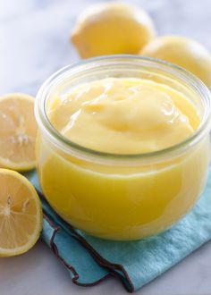 someone is spooning lemon custard into a jar