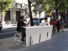 a man sitting at a desk on the side of a street next to a tree