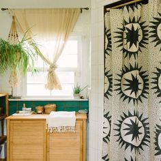 a bathroom with a shower curtain, sink and wooden cabinet in the corner next to a potted plant