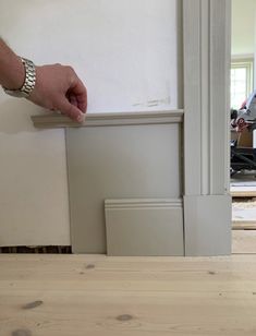 a person is holding the edge of a piece of wood in front of a door