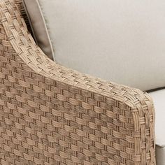 a wicker chair with white cushions on it's armrests and back