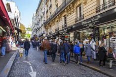 many people are walking down the street in front of shops