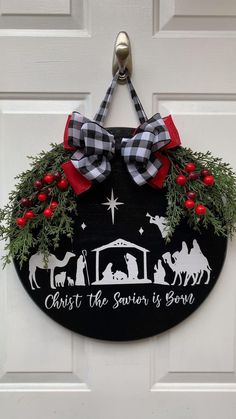 a door hanger decorated with christmas wreaths and nativity saying, christ the savio is born