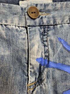 blue paint is being applied on the back pocket of a pair of jeans that have holes in them