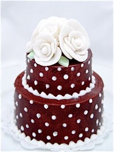 a three tiered cake with white flowers on the top and polka dots on the bottom