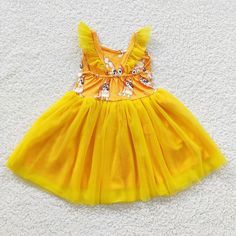 a yellow dress is laying on the floor next to a white carpet and a pair of scissors