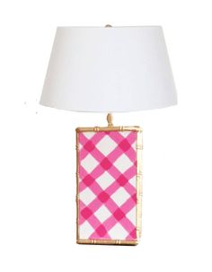 a pink and white table lamp with a white shade on it's side, against a white background