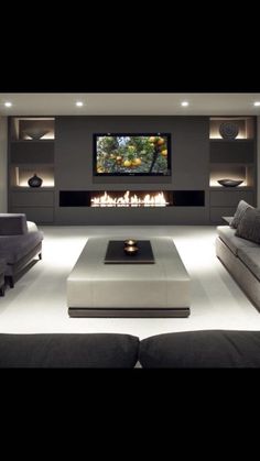 a living room with couches and a flat screen tv on the wall in front of a fireplace