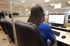 a woman sitting at a desk in front of a computer monitor with headphones on