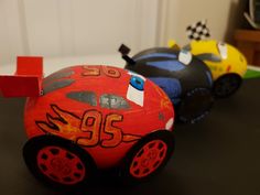 two toy cars sitting on top of a black table next to each other in the shape of race cars