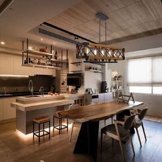 an open kitchen and dining area with wooden floors, white walls and ceiling lights that are suspended from the rafters