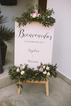 a sign with flowers and greenery on it