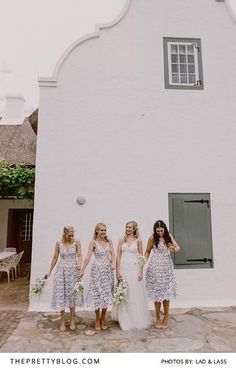 a group of women standing next to each other in front of a white building