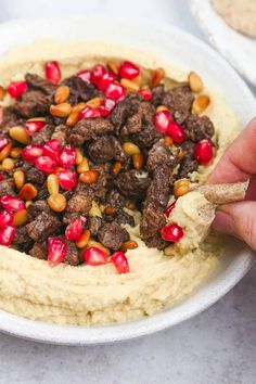 a bowl filled with hummus and meat topped with pomegranates