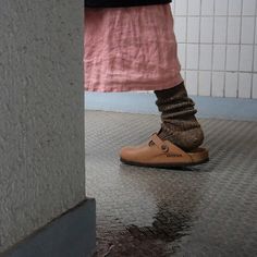 a person wearing brown shoes standing in front of a wall