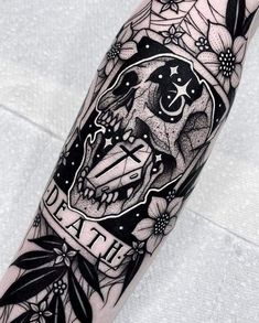 a black and white image of a skull with flowers on it's arm, in the