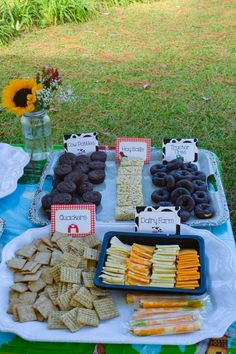 an assortment of snacks displayed on a table in front of a flower vase and sunflower