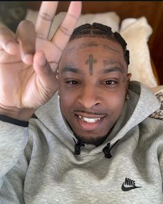 a man with tattoos on his face making the peace sign