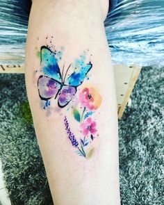 watercolor tattoo on the leg of a woman with flowers and a butterfly painted on it