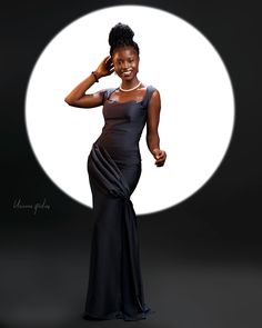 a woman in a long black dress posing for a photo with the moon behind her