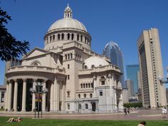 people sitting on the grass in front of a large building with a domed roof and columns