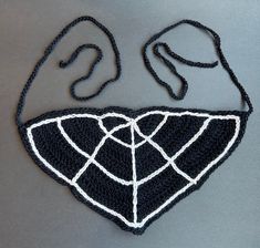 a crocheted black and white bib with two ears on the side, attached to a string