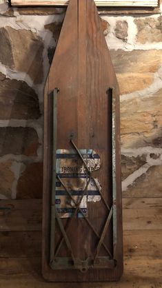 a wooden clock hanging from the side of a stone wall